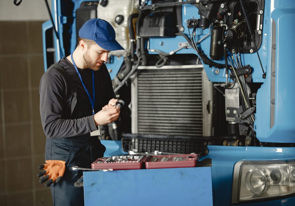 Men repair a truck. Man teaches repair a car. Two men in uniform